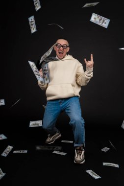 Genç mutlu iş adamı, siyah arka planda izole edilmiş bir yığın para rublesiyle dans ediyor. Nakit para tabancası. Seçici odak, ana konu - erkek.