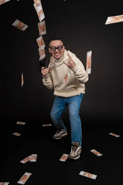 Joven hombre de negocios feliz bailando con una pila de rublos de dinero aislado en el fondo negro. Pistola de dinero en efectivo. Enfoque selectivo, tema principal - hombre. —  Fotos de Stock