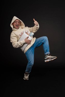 Defteri ve kara arka planda izole edilmiş bir yığın parası olan genç ve mutlu bir iş adamı. Seçici odaklanma, ana konu - adam. İlginç bir iş konsepti.