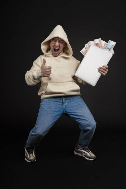 Defteri ve kara arka planda izole edilmiş bir yığın parası olan genç ve mutlu bir iş adamı. Seçici odaklanma, ana konu - adam. İlginç bir iş konsepti.