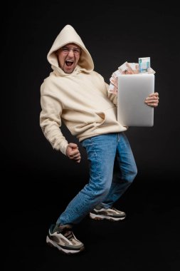 Defteri ve kara arka planda izole edilmiş bir yığın parası olan genç ve mutlu bir iş adamı. Seçici odaklanma, ana konu - adam. İlginç bir iş konsepti.