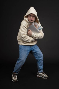 Defteri ve kara arka planda izole edilmiş bir yığın parası olan genç ve mutlu bir iş adamı. Seçici odaklanma, ana konu - adam. İlginç bir iş konsepti.