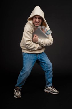 Defteri ve kara arka planda izole edilmiş bir yığın parası olan genç ve mutlu bir iş adamı. Seçici odaklanma, ana konu - adam. İlginç bir iş konsepti.