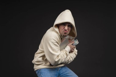 Defteri ve kara arka planda izole edilmiş bir yığın parası olan genç ve mutlu bir iş adamı. Seçici odaklanma, ana konu - adam. İlginç bir iş konsepti.