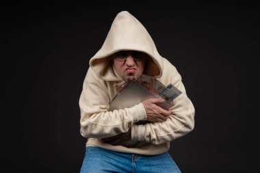 Defteri ve kara arka planda izole edilmiş bir yığın parası olan genç ve mutlu bir iş adamı. Seçici odaklanma, ana konu - adam. İlginç bir iş konsepti.