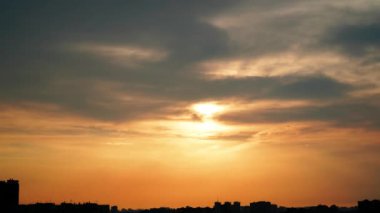 Arka planda şehirle birlikte bulutlu günbatımının zaman akışı