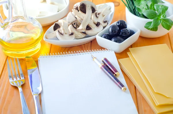 Öppna anteckningsboken och ingredienser till lasagne — Stockfoto