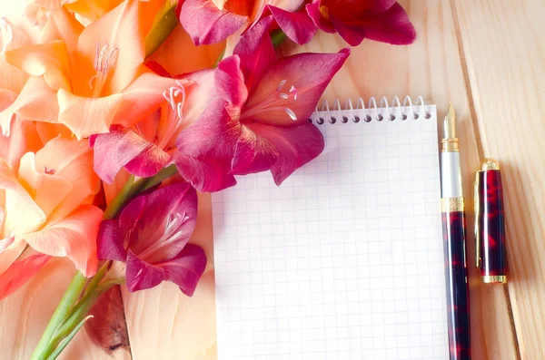 Notebook en bloemen op houten achtergrond — Stockfoto