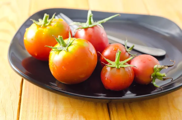 Tomaten in een zwarte kom — Stockfoto