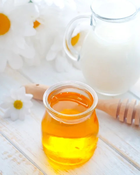 Miel fresca en el banco de vidrio y leche en jarra — Foto de Stock