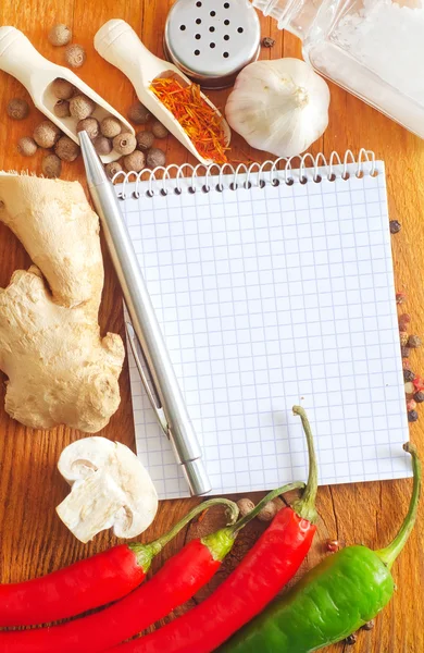 Notebook for recipes and spices on wooden table — Stock Photo, Image