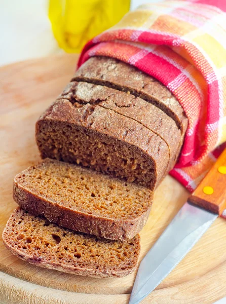 Čerstvý chléb a nůž na dřevěné desce — Stock fotografie