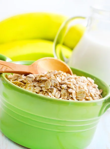 Oat flakes in the green bowl with banana and milk — Stock Photo, Image