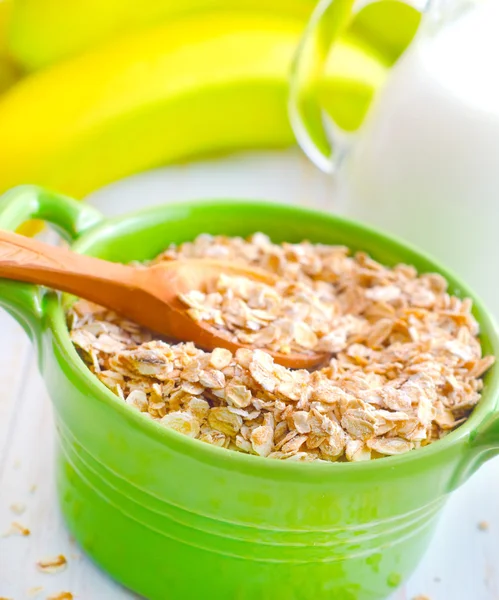 Oat flakes in the green bowl with banana and milk — Stock Photo, Image