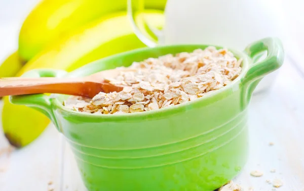 Oat flakes in the green bowl with banana and milk — Stock Photo, Image