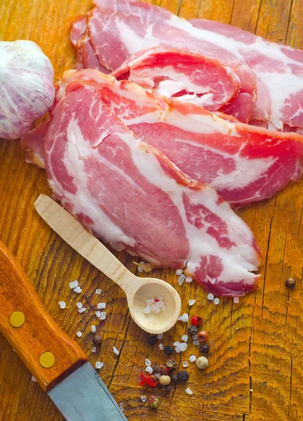 Tocino con especias aromáticas en el tablero de madera — Foto de Stock