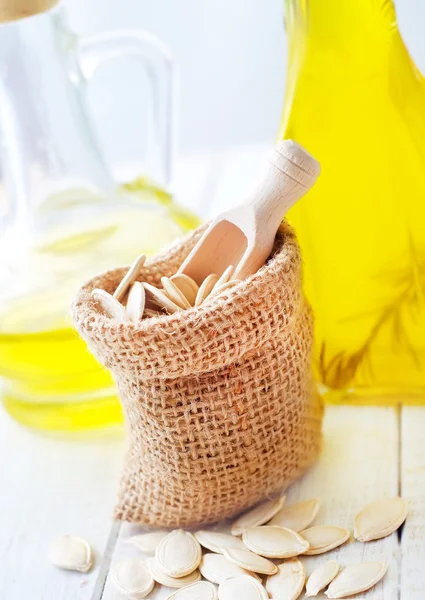 Dry pumpkin seed in sack, oil in glass bottle — Stock Photo, Image