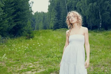 güzel sarışın kız çiçekleri ile yeşil alan. kırsal sahne