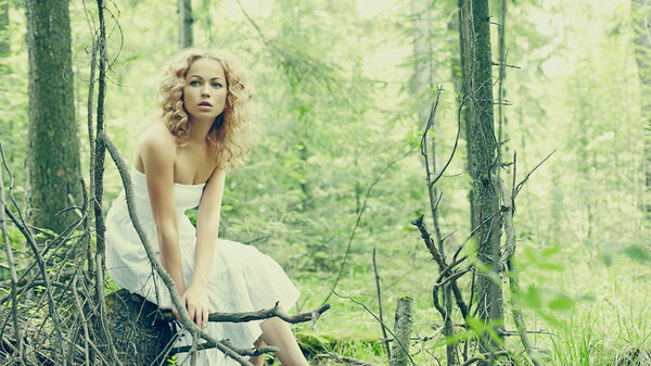 Fashion portrait of young beautiful blond woman in forest