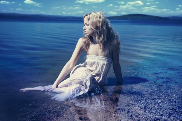 Young sexy blond woman in the blue water in wet white dress — Stock Photo, Image