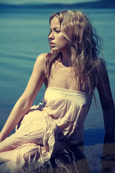 Young sexy blond woman in the blue water in wet white dress — Stock Photo, Image