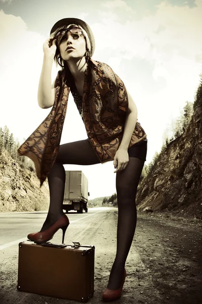 Девушка автостопом с чемоданом — стоковое фото