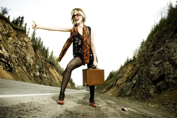 Дівчина автостоп з валізою — стокове фото
