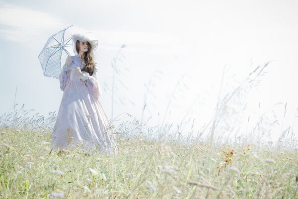 Beautiful woman in vintage dress walking across a field