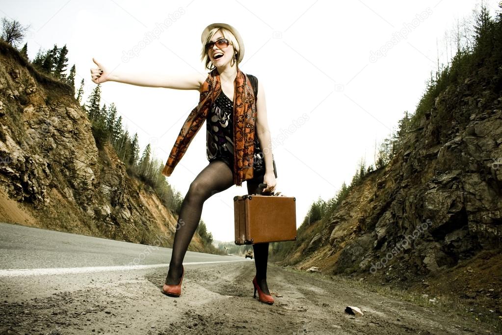 girl hitchhiking with suitcase