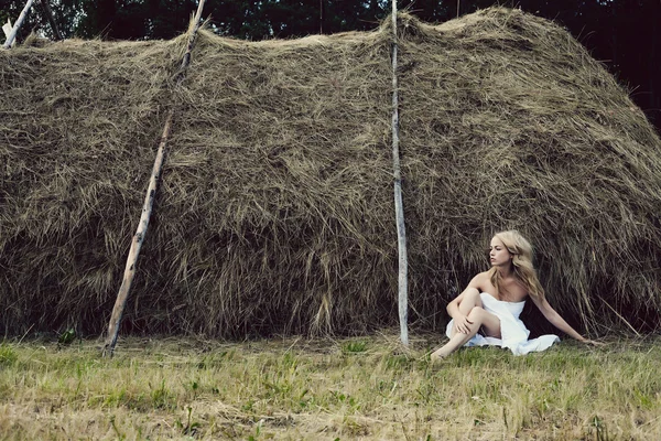 Beautiful sexy young woman near a haystack — Stock Photo, Image