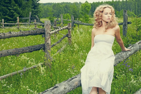 Vacker blond tjej på gröna fält med blommor — Stockfoto