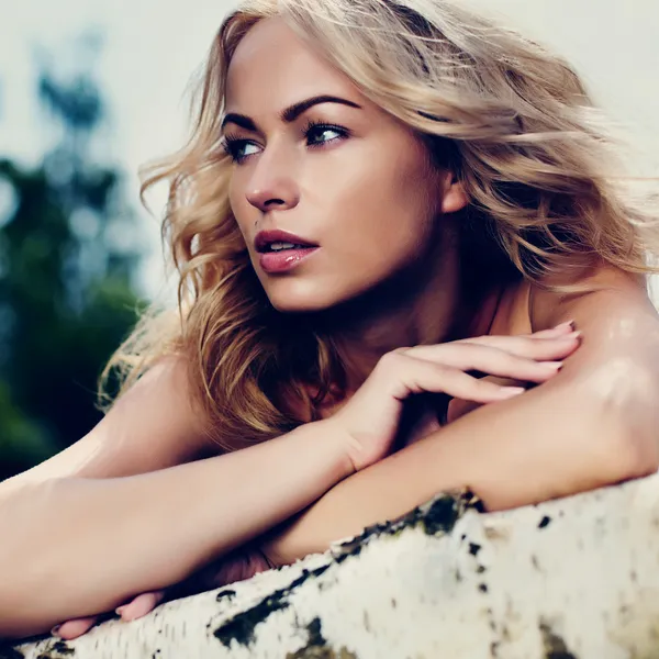 Woman with blonde hair on branch. Looking around — Stock Photo, Image