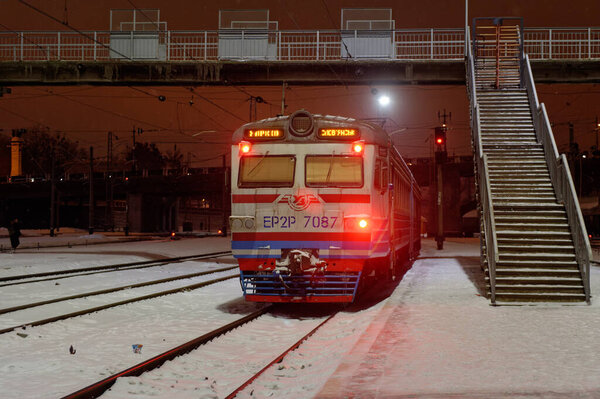Харьков, Украина - 28 января 2022 года: Старый электропоезд ER2R Украинских железных дорог отправляется со станции платформы Харьковского пассажирского железнодорожного вокзала. Ночное фото.