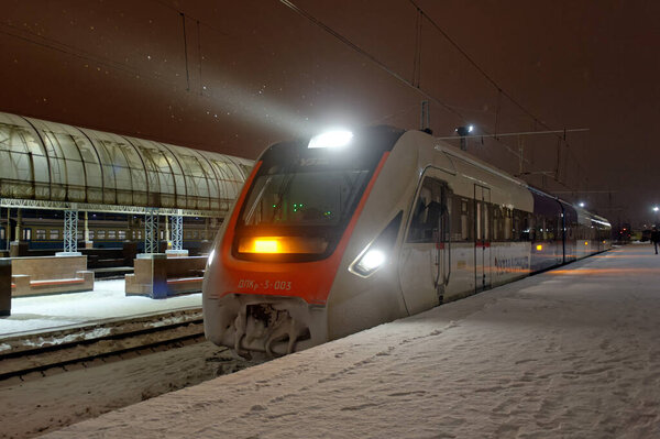 Харьков, Украина - 28 января 2022 года: Пассажирский поезд железной дороги ДПКр-3 отправляется со станции платформы на Харьковском пассажирском вокзале. Ночное фото.