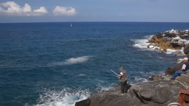 Man fishing on rocky sea coast — Stock Video