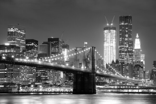New York City Brooklyn Bridge black and white with downtown skyline over East River.