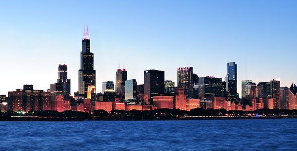 Chicago city downtown urban skyline panorama at dusk with skyscrapers over Lake Michigan with clear blue sky.