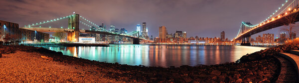 New York City Manhattan Bridge and Brooklyn Bridge with downtown skyline panorama over East River at night