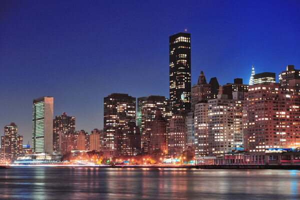 New York City Manhattan midtown skyline at night over East River.