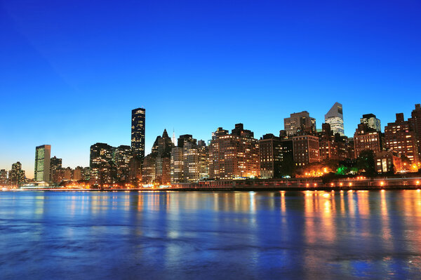 New York City Manhattan midtown skyline at night over East River.
