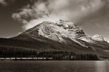 Kanada Banff Ulusal Parkı 'nda gün batımında yansımalı ve sisli dağ gölü.
