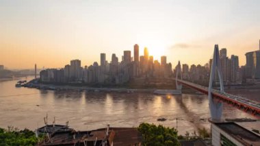Chongqing şehrinin kentsel mimari manzarası ve Çin 'de gün batımından batımına kadar nehir üzerinde köprü.