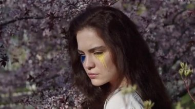 Young attractive girl portrait with Ukrainian flag in the spring cherry garden 