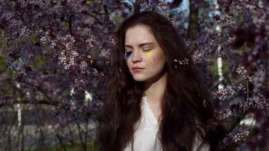 Young attractive girl portrait with Ukrainian flag in the spring cherry garden 