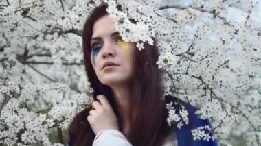 Young attractive girl portrait with Ukrainian flag in the spring cherry garden 