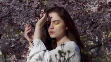 Bahar kiraz bahçesinde Ukrayna bayrağıyla genç çekici kız portresi 