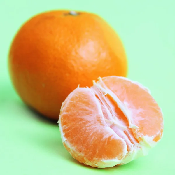Yeşil zemin üzerine soyulmuş portakal — Stok fotoğraf