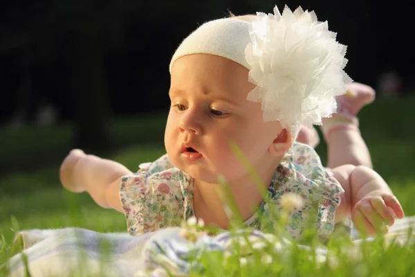 Adorable baby girl lying on green summer lawn — Stock Photo, Image