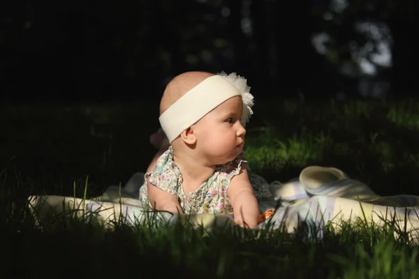 Adorable baby girl lying on green summer lawn — Stock Photo, Image