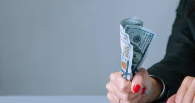 Para, gelir, gelir ve tasarruf sembolü olarak Amerikan Doları banknotlarını elinde tutan bir iş kadını. Boşluğu kopyala.